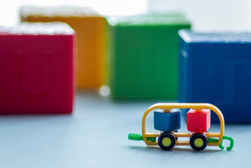 MACRO PHOTOGRAPHY OF LITTLE CAR TOY WITH CUBE SHAPES AND NORMAL CUBES IN THE BACKGROUND