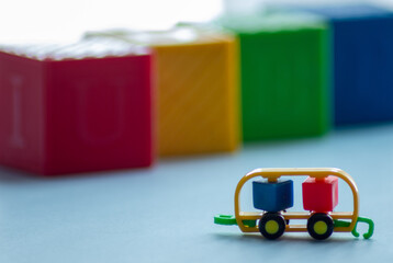 Fototapeta premium MACRO PHOTOGRAPHY OF LITTLE CAR TOY WITH CUBE SHAPES AND NORMAL CUBES IN THE BACKGROUND