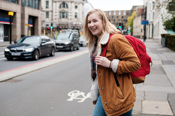Fototapeta premium Young blonde woman crossing the road and smiling.