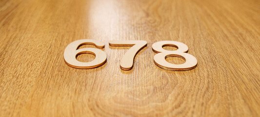 Flatley, side view of large wooden numbers six, seven and eight lying in order on a wooden background