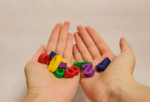 Multi-colored bright children's numbers for development from zero to nine lie in a handful in both palms of the hand