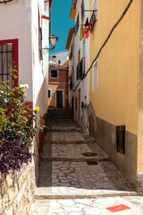 Finestrat, Alicante province, Spain. Beautiful quiet narrow street of small Finestrat village old town with old buildings, stone pavement at sunny day