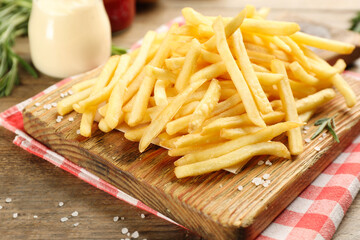 Delicious french fries served on wooden table, closeup