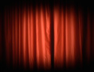 A spotlight on red theater curtains, creating a vignette around the bright center. Front shot.