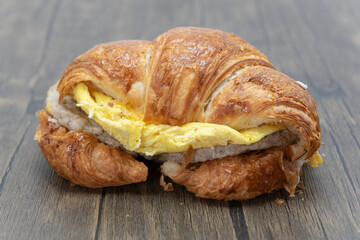 Delicious croissant sandwich loaded with scrambled eggs, melted cheese, and sausage patty for a complete meal.