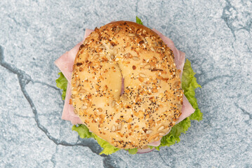 Overhead view of everything bagel bun envelops this non traditional ham sandwich loaded with...