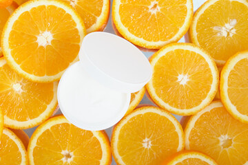 white cream jar on a background of sliced oranges, face and body cream with the addition of orange oil concept, mock up, no label