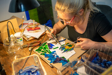 young woman is making a stained glass,  stained glass crafting, soldering pieces of glass