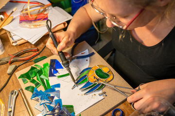 soldering the stained glass window, woman is making a stained glass, soldering the stained glass...
