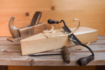 Unusual carpentry tool.Hand plane,scraper or woodcutter for carpenter.Curved knife with handles peeling bark logs,planing.Drilling shallow hole gimlet in soft wood,board.Selective focus on shavings