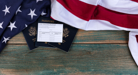 North America flag with covid 19 Vaccination record card and US Passports on fade blue rustic...
