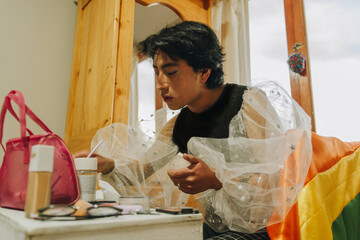 Joven queer eligiendo que maquillaje usar en su habitación 