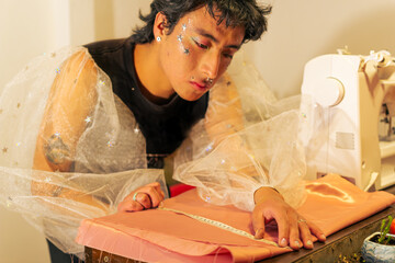 Joven diseñador de modas queer concentrado trabajando 