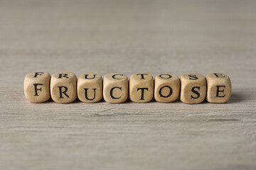 Word Fructose made of wooden cubes on table, closeup