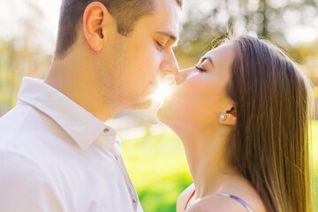 Close-up of the faces of a beautiful couple laughing up close before a kiss with closed eyes against the backdrop of a sunset while traveling.