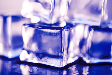 Wet ice cubes on blue background, close-up