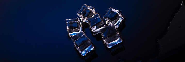 Wet ice cubes on blue background top view