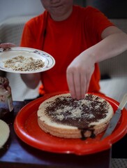 The boy prepares a sweet cake smears waffles with chocolate and jam