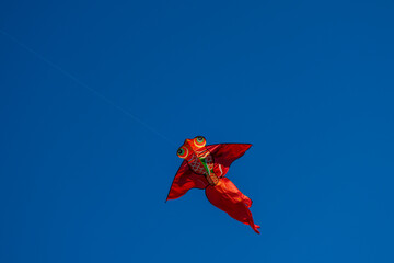 red yellow goldfish kite high in a blue summer sky