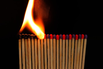 A row of burning matches on a black background. The flame moves from the match to the match. Fire is inevitable