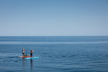 Naklejka premium Family of four on stand up paddle boards on open water.