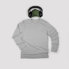 Flat lay men's grey heather long sleeve t-shirt mock up with headphones and green cap on clear gray background