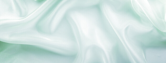 light green organza fabric draped with large folds, delicate textile background