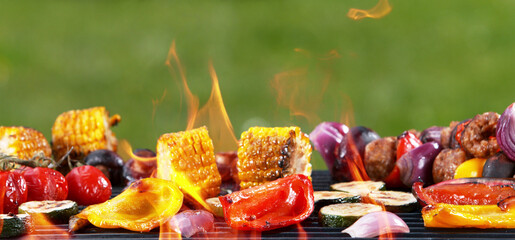 Assorted delicious grilled vegetables placed on grill with fire.