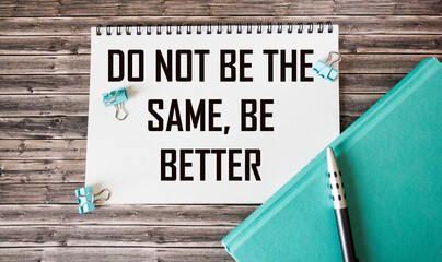 Notebook with text Don't be the same, be better in conceptual image on a wooden background