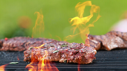 Grill grid with beef steaks in fire