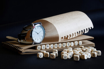 A wristwatch, a notebook and the word linguistics, made up of wooden cubes, on a dark background. Concept for research in linguistics and language history, school or college education - obrazy, fototapety, plakaty