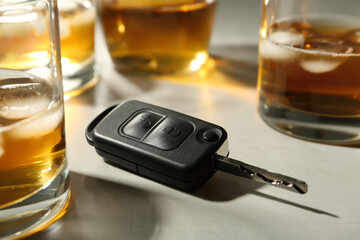 Car key near glasses of alcohol on table. Dangerous drinking and driving