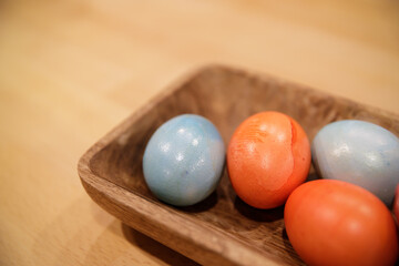 several painted in different color of chicken eggs lie in a wooden tray. selective focus.High quality photo