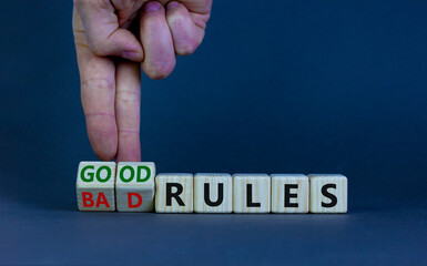 Good or bad rules symbol. Businessman turns wooden cubes and changes words 'bad rules' to 'good rules'. Beautiful grey table, grey background, copy space. Business and good or bad rules concept.