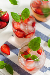 Homemade refreshing strawberry lemonade in glasses and jug with fresh strawberries and mint leaves. Summer drink 