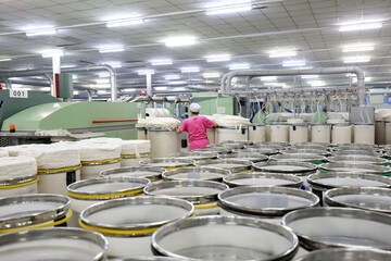 The female worker is busy on the production line in a spinning factory.