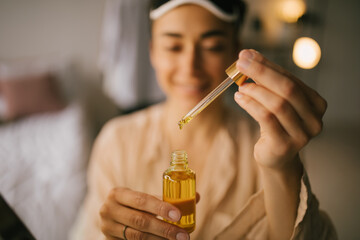 Portrait of beautiful young woman holding face oil. Beauty cosmetic concept.