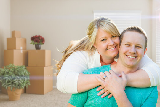 Happy Caucasian Couple Inside Empty Room with Cardboard Boxes - Moving Into New House