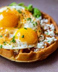 Waffle with sunny side up eggs, avocado, and feta cheese