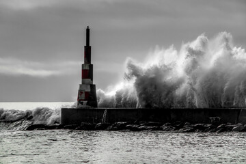 Obraz premium Giant waves breaking on the breakwater and the lighthouse