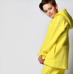 Clothes for schoolchildren. Studio portrait of a little boy in a warm yellow sports suit on a white background. Confident schoolboy boy standing smiling near free space for text. Banner.