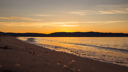 Naklejka premium Long distance view of small waves crushing the shore of Poetto beach at sunrise