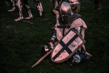 a knight on knees outdoors on a battlefield
