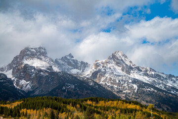 dramatic  snow capped mountain peaks of the Grand teton mountain range and colorful autumn foliage in Jackson, Wyoming.