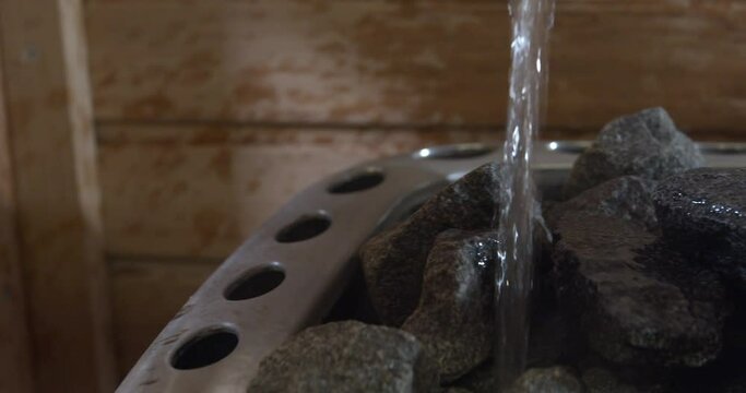 Pouring water on the rocks from a sauna heater. Water evaporated by hot stones