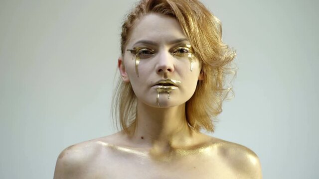 Golden makeup. Fashion art skin. Woman gold face portrait closeup.