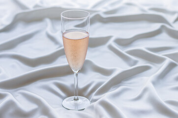 A glass of Rose wine on wavy satin cloth. Stay home concept.