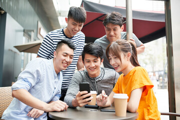 group of young asian adults looking at cellphone together