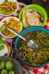 Quelites en olla de peltre con cuchara, comida mexicana del campo, con tortillas y salsa de mango