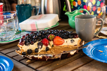 A cut in half fruit tart sits on top of a table during a party outside.